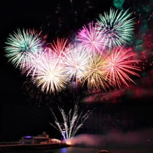 Farbenfrohes Silvesterfeuerwerk über einem Schiff auf dem Wasser