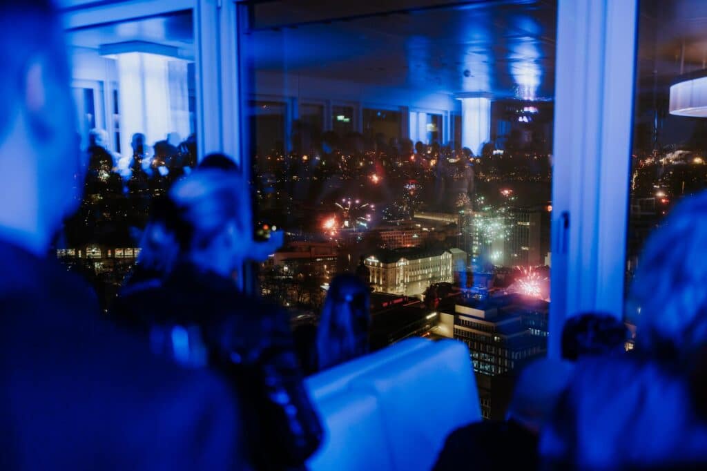 Gäste genießen das Silvesterfeuerwerk über Hamburg vom Panoramadeck