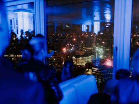 Gäste genießen das Silvesterfeuerwerk über Hamburg vom Panoramadeck
