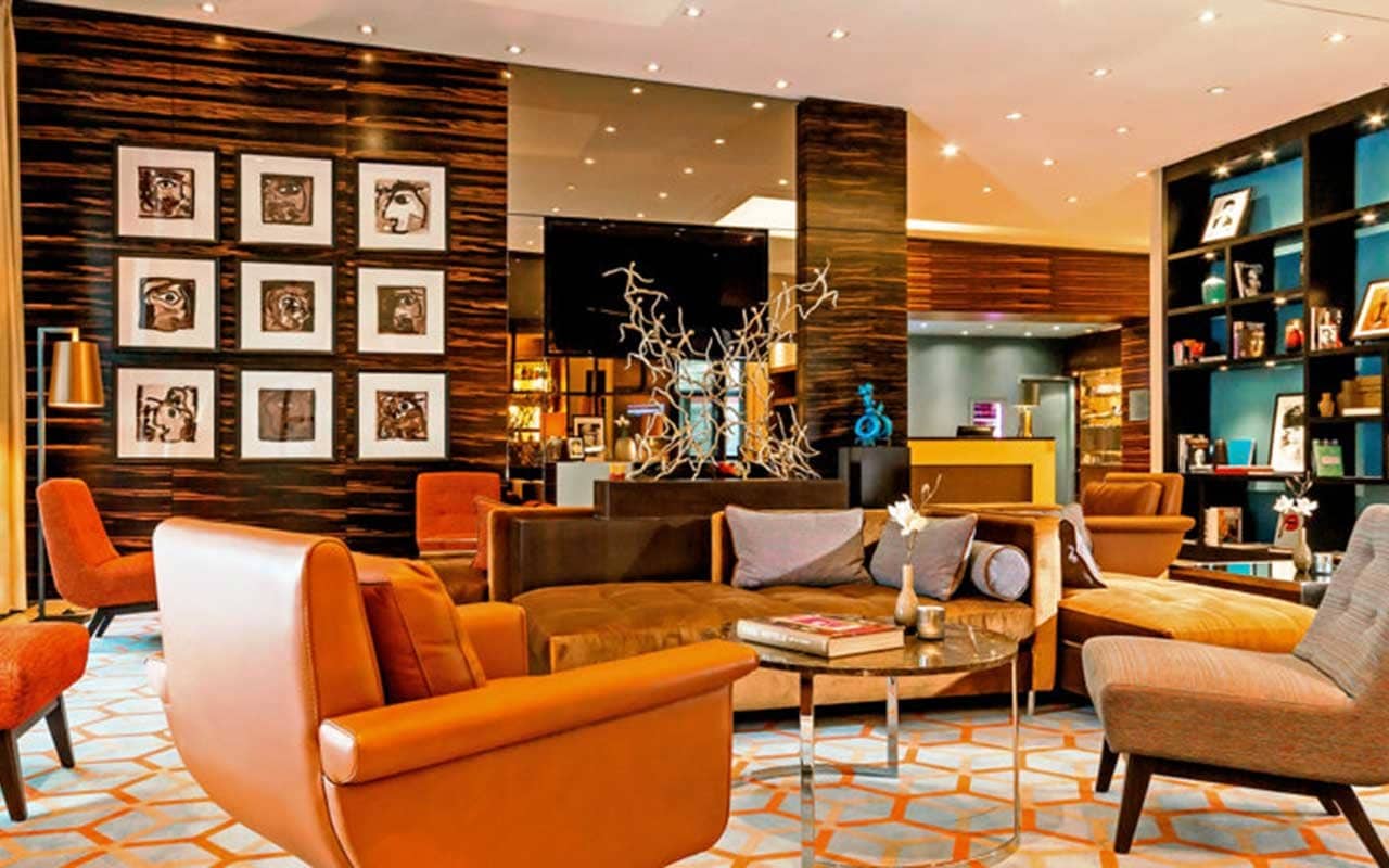 Moderne Lounge mit orangefarbenen Sesseln und Holzvertäfelung im Ameron Hotel Regent, perfekt für Silvester