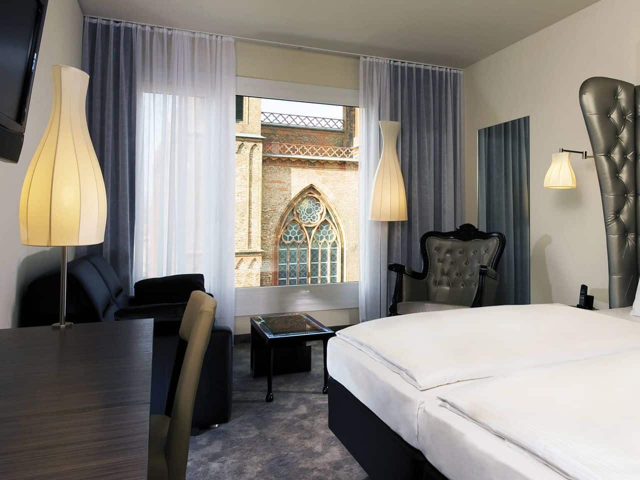 Komfortables Zimmer im ARCOTEL John F Berlin mit Aussicht auf eine historische Kirche, perfekt für Silvester