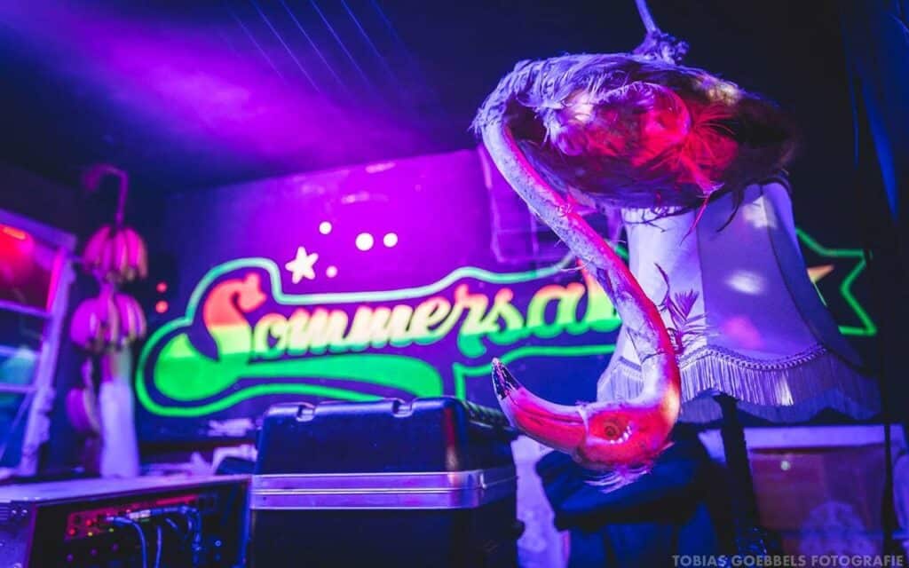 Neonlichter und Retro-Dekoration im Sommersalon für die Silvesterparty 2024.