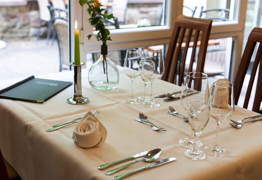 Elegant gedeckter Tisch mit Kerzen und feinem Besteck im Restaurant des Hotel Mainpromenade