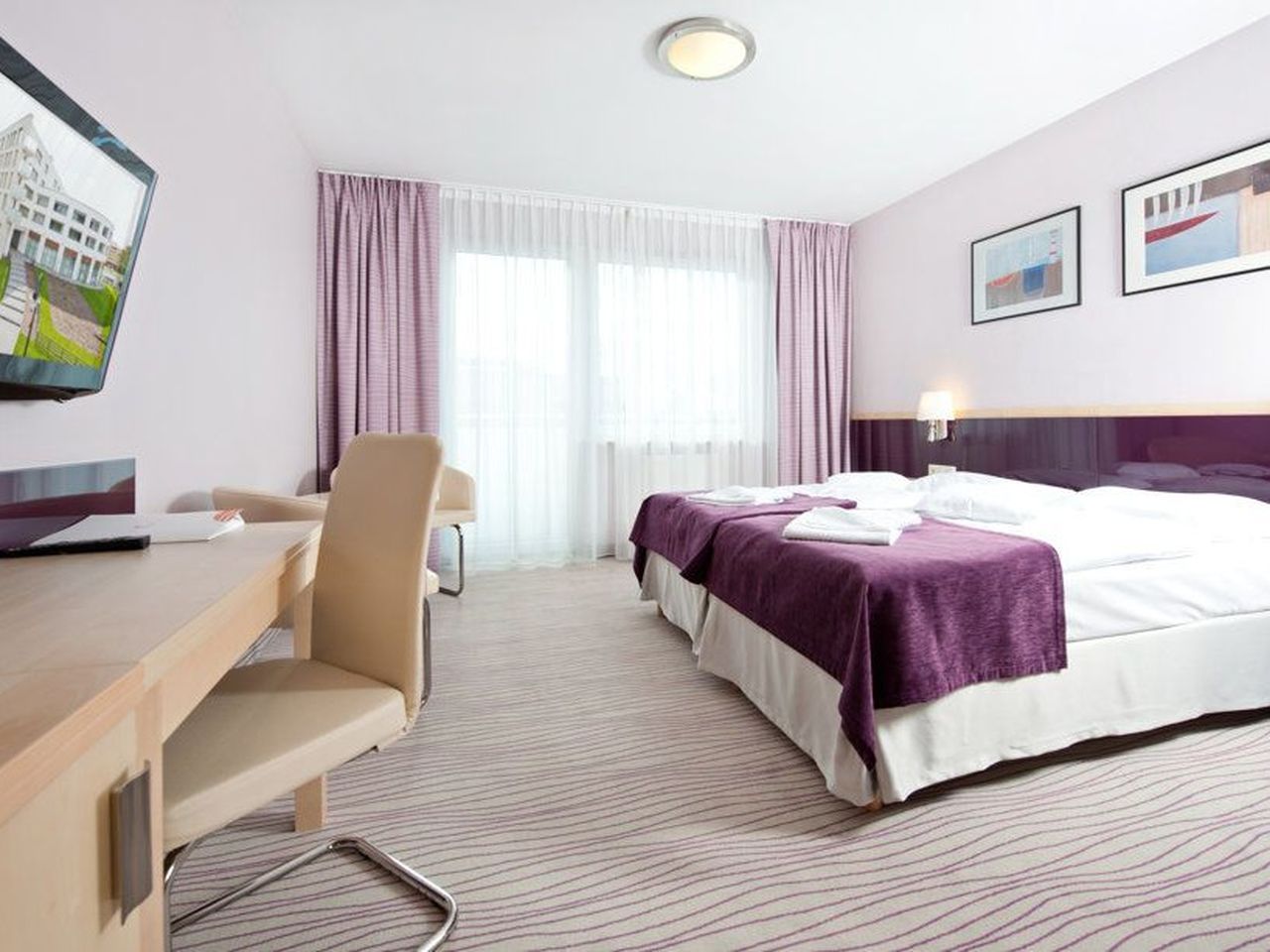 Modern eingerichtetes Hotelzimmer mit violetten Akzenten im INTERFERIE MEDICAL SPA - Hotel zu Silvester