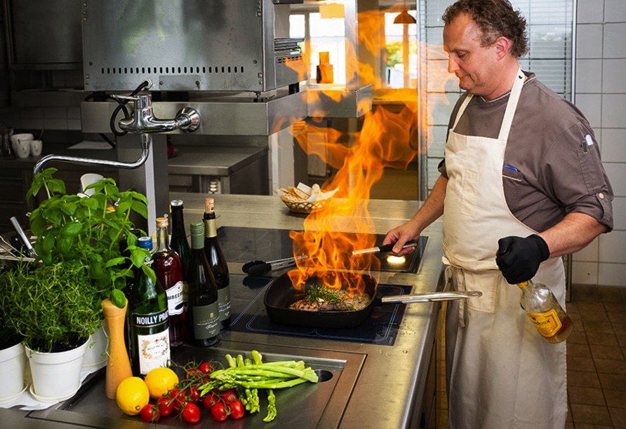 Küchenchef flambiert ein Steak für das Silvester-Menü