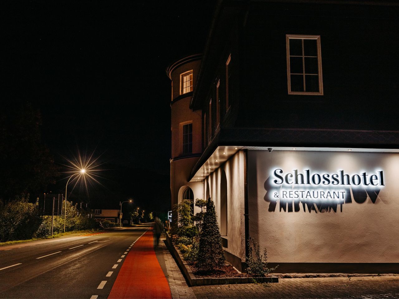 Nachtaufnahme des Schlosshotel Brilon-Wald mit beleuchtetem Logo