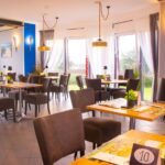 Eleganter Essbereich des Inselhotels Kleiner Bodden mit gedeckten Tischen und Blick ins Grüne – ideal für Silvesterfeiern.