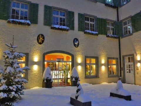 Außenansicht des JUFA Hotel Meersburg im Winter mit Silvesterbeleuchtung