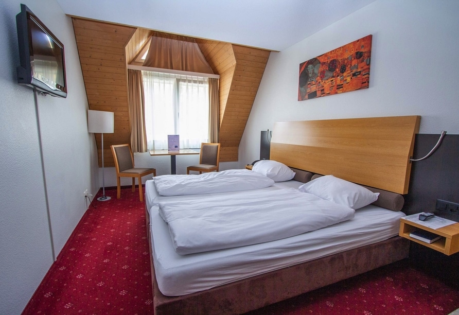 Gemütliches Doppelzimmer im City Hotel Brunnen mit rotem Teppich und Holzelementen