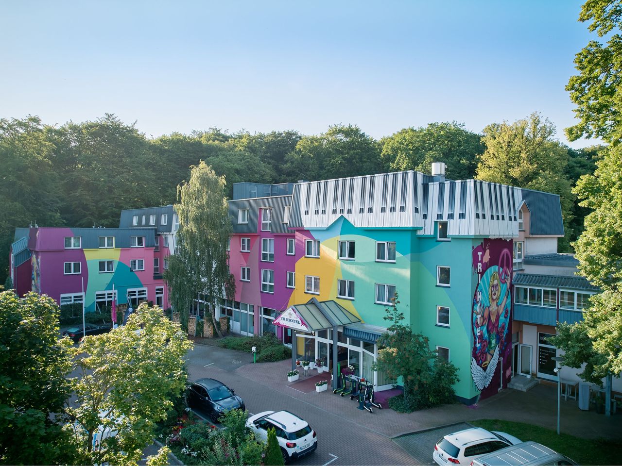 Farbige Fassade des TRIHOTEL Rostock mit Blick auf den Schweizer Wald