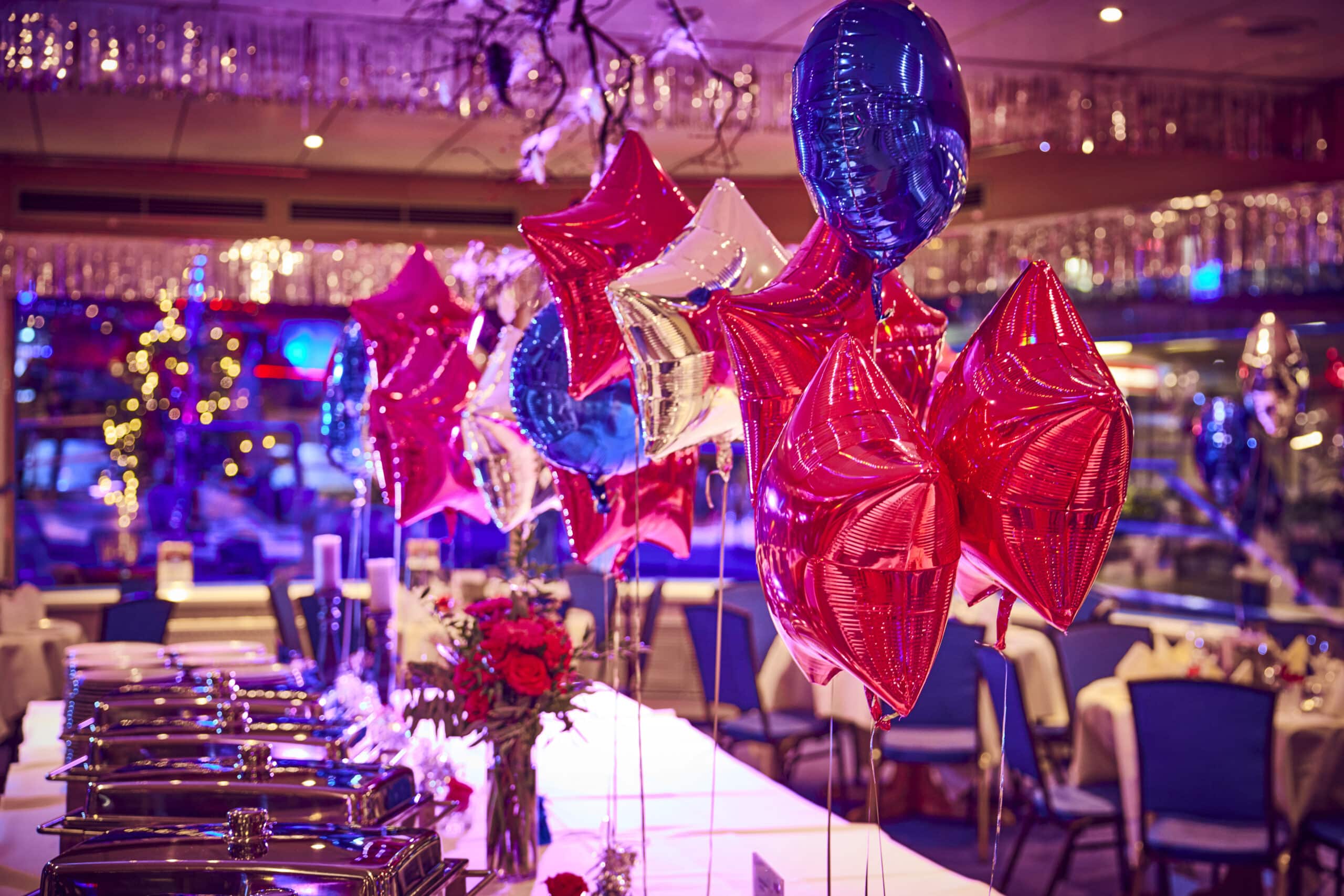 Silvesterbuffet und festlich dekorierter Innenraum der MS Hanse Star mit Ballons und Lichterglanz