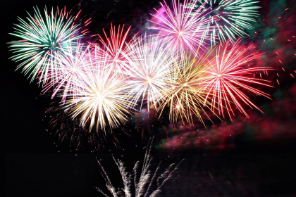 Farbenfrohes Silvesterfeuerwerk über einem Schiff auf dem Wasser